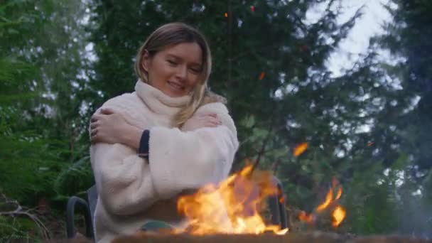 週末の休暇中に薪を燃やしたポートレート カルムの女性 緑のスプルースの森で燃えることに満足する観光客 リラックスした笑顔の女性は燃える火で自然旅行を楽しむ — ストック動画