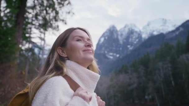 バックグラウンドの岩山の山頂の遠隔自然の目的地でのポートレートハイカーの観光客 曇りの日の屋外で火の森を探索する女性の旅行者 山でハイキング観光バックパックを持つ女性 — ストック動画