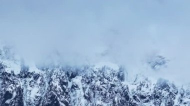 Washington kopya geçmişi. Kış günü bulutların içinde güzel yüksek dağ zirveleri. Karla kaplı kayalık zirvesiyle ilham verici bir manzara. Karlı uçurumlarla dolu destansı doğa manzarasında bulutlu bir gün.