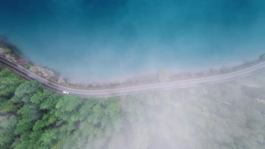 Tepeden tırnağa sinematik arka plan ve fotokopi alanı. Bulutların üzerinde uçan İHA güzel yağmur ormanlarını kaplıyor. Evergreen Park 'taki mavi dağ gölü boyunca Washington 4K hava durumu.