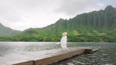 Sinematik Jurasik doğa dağ manzaralı havadan ahşap iskele 4K. Oahu adasındaki destansı manzaralarda gezen bir turist. Hawaii adasındaki gizli kumsal gölünü araştıran kadını takip eden kamera.