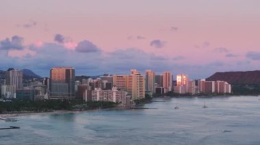 Oahu Adası 'ndaki Waikiki otellerinin üzerinde gökyüzü. Hawaii seyahat hedefi ABD. Waikiki yaz tatili otellerinde gün batımı sineması. Modern okyanus manzaralı otellerde parlayan güzel altın güneş 4K