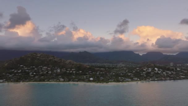 ランカイビーチの上の緑の丘の上に巣立った休暇の家の空中ビュー 夜明けの熱帯の自然景観 ハワイ島の上空に太陽が点灯する雲 夏休みの背景について オアフ — ストック動画