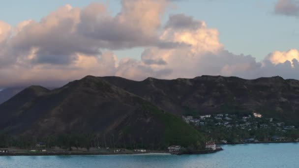 ハワイ島の上空に太陽が点灯する雲 夏休みの背景について オアフ島観光 ランカイビーチの上の緑の丘に巣立ったバケーションハウス 夜明けの風光明媚なトロピカルな自然景観を眺める — ストック動画