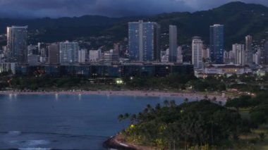 Şehir merkezinin gece manzarası. Oahu 'daki sahil şeridi şehrinin güzel şehir manzarası. Şehir ışıkları mor gün batımında Hawaii 4K. Honolulu şehir merkezinde, pembe günbatımında. Manzaralı Waikiki ufuk çizgisi manzarası