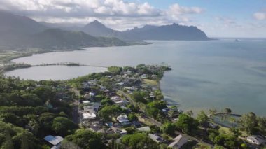 Mavi okyanustaki Kaneohe Körfezi 'ne bakan yeşil tepedeki evler. Kualoa çiftlik manzaralı küçük bir köy. Güneşli bir gün Hawaii. Oahu adasının rüzgarlı sahillerinde bulunan Kahaluu yerleşim bölgesi.