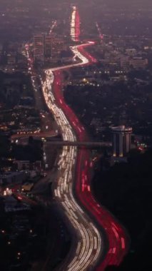 Dikey video güdümlü zaman aşımı büyük şehir Los Angeles 'ta hızlı gece trafiğinin parlak gece hareketini hızlandırıyor. Beyaz farlar ve kırmızı ışıklarla yola bak. Işıklar, parlayan caddeler, binalar...