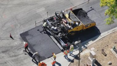 Los Angeles, Kaliforniya, ABD, yeniden yüzeye çıkış süreci Mart 4, 2024: Bir banliyö caddesini yeniden yüzeye çıkarmak için asfalt kaldırım kullanan yüksek görüşlü işçilerin hava görüntüsü
