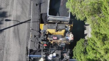 Gökyüzünün altında asfalt kaldırım teçhizatı kullanarak kentsel yol yapım ekibini yakalama görüntüsü yükseldi. Çekim 4K. 