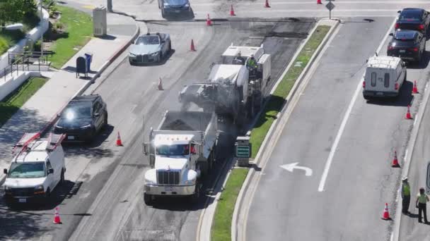 ロサンゼルス カリフォルニア アメリカ 道路再浮上プロセスマート4 2024 オーバーヘッドビューは 白いトラックと道路作業クルーをキャプチャし 郊外の通りに新鮮なアスファルトを敷設する機械を舗装します — ストック動画