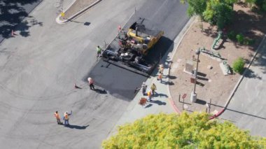 Los Angeles, Kaliforniya, ABD, 4 Mart 2024 'te yeniden yüzeye çıkma süreci: Yüksek açılı çekim, güneşli bir günde inşaat ekipmanları ve mürettebatla taze asfalt serme sürecini kaydediyor. 4K.