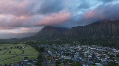 Oahu adasındaki Kaneohe kasabasının havadan görünüşü. Pembe gündoğumunda manzaralı dağ sırtı. Honolulu Watershed Ormanı 'nı kaplayan yağmur bulutlarındaki ilk güneş ışınları. Dik orman tropikal dağ