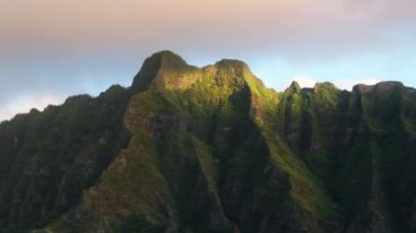 Jurassic Park sahnesinin yemyeşil manzarası. Güneşin doğuşundaki nefes kesici volkanik ada görüntüsü. Sinema zirveleri, şafak vakti tropikal adada altın gün ışığında çarpıcı bir şekilde parlar.