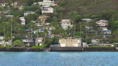 Zengin insanlar Hawaii adasında tropikal tatilin tadını çıkarıyorlar. Lanikai sahilindeki okyanus manzaralı villalar. Sahildeki yazlıkların modern binaları kiralık. Oahu Adası Emlak Konsepti