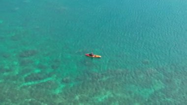 Lanikai sahilindeki turist turunda renkli bir kanoyla kürek çekerken mutlu ol. 4K saydam mavi sularıyla Oahu kıyısının havadan görüntüsü. Yaz gezisi. Her yere git. Açık hava sporları aktivitesi