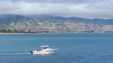 Oahu adasının kuzey kıyısında köpekbalığı turu. Yazın güneşli havalarda Hawaii 'de su sporu etkinliği. Haleiwa limanından hareket halindeki Oahu dağlarıyla birlikte ayrılan küçük bir balıkçı teknesi.