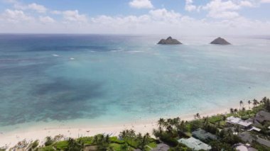 Hawaii manzaralı Pasifik manzarası. Güneşli bir sabahta Lanikai sahilinin havadan manzarası. Yeşil hindistan cevizi palmiyeleriyle çevrili, deniz kıyısında uçan insansız hava aracı. Oahu adasındaki güzel sahil.