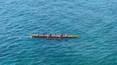 İHA, spor takımının kanoyla kürek çekmesiyle birlikte uçuyor. Geleneksel Hawaii kanosu Oahu 'da kayıkla gezen atletizm insanlarının genel manzarası. Açık mavi okyanus ABD 'de su sporu aktivitesi