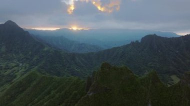 Hawaii 'ye seyahat. Bulutlu Kualoa vadisi dağları üzerinde dramatik hava manzarası. Jurasik doğa ile yeşil orman manzarasının üzerinde insansız hava aracı vuruldu. Bulutlu bir günde nefes kesici volkanik dağlar