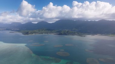Kaneohe Körfezi 'nde açık deniz mavisi. Havai Dağı 'nın beyaz bulutlardaki tepeleri. Hawaii turizmi 4K İHA 'sı yaz günü Kaneohe Sandbar üzerinde mavi gökyüzüyle uçuyor. Oahu adası seyahat geçmişi