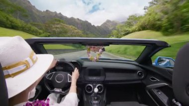 Çiçekli zarif kadın destansı manzaranın tadını çıkarıyor. Kadın Oahu Adası 4K 'dan geçiyor. H3 otobanından geçen mavi üstü açık arabalı mutlu turist. Cabriolet açık arabasından manzaralı Hawaii manzarası