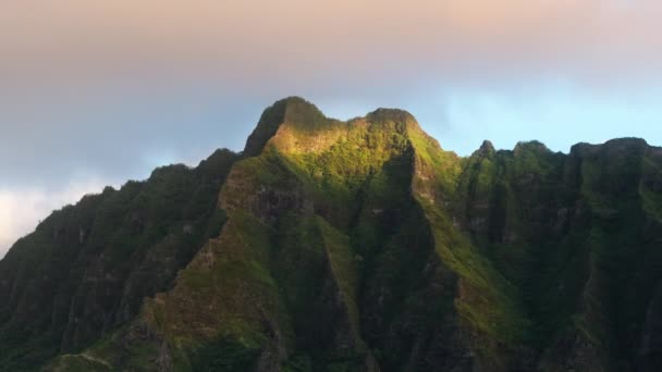 夜明けにトロピカルアイランドの黄金の日差しで劇的に上昇するシネマティックなピーク ジュラシックパークシーンの緑豊かな風景 日の出の光の中で息をのむ火山の島の自然の空中撮影 — ストック動画