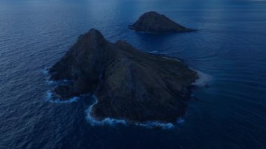 Rocky Na Mokulua adaları Oahu adasının rüzgarlı sahillerinde gece vakti koyu mavi ay ışığında. İnsansız hava aracı kamerasının Hawaii turizm geçmişi. Açık hava macera seyahati için manzara manzarası, USA 4K