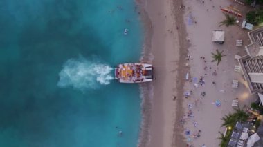 Sarı turist katamaranının yukarıdan görünüşü. Waikiki sahilinde popüler su eğlencesi. Oahu adasındaki Waikiki kıyısında gün batımı gezisi. Hawaii turizm geçmişi. İnsanlar yaz tatilinin tadını çıkarıyor. 