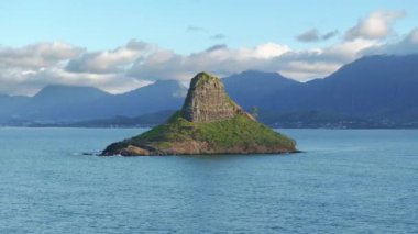 Hawaii 'deki Oahu Adası manzarası. Çinlilerin Şapka Adası 'nın kıyısındaki hindistan cevizi palmiyeleri. Kualoa Çiftliği' nin arka planında hareketli bir dağ var. Bulutlu gökyüzünün arka planında Mokolii bazalt adası