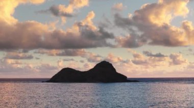 Oahu turizm kavramı. Güneş doğarken rüzgârlı sahillerde iki küçük ada. Na Mokulua adalarının siluetleri 4K bulutlarının altında mavi okyanusta. Hawaii adalarındaki doğal manzaranın sinematik arka planı