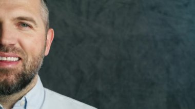 Yarım yüzlü, kendine güvenen takım elbiseli iş adamı. Gri arkaplanda boşluk kopyala. Yakışıklı orta yaşlı profesyonel çalışanın yakın çekimi. Olumlu gülümseyen sakallı adam doğrudan Amerika 'ya bakıyor.