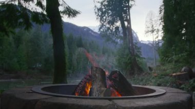 Washington Doğa Parkı 'nda statik şömine çekimi. Açık hava kamp macerası seyahati. Akşamları yeşil ormanda şenlik ateşi dumanla yanıyor. Dağ ladin ormanında yanan kamp ateşi.