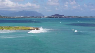 İnsansız hava aracı, doğal sığınağı olan küçük düz yeşil bir adada uçuyor. Kailua Körfezi 'ndeki Popoia adasındaki hava manzarası. Hareket arka planında güzel bir Hawaii adası manzarası. Bulutlarla kaplı yeşil dağlar