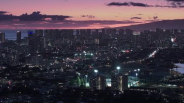 Pasifik 'teki Oahu adasının modern şehir manzarası. Honolulu şehir merkezi gün batımı manzarası. Honolulu 'nun başkenti Hawaii' de sinematik hava. Şehir üzerinde gece aydınlanan pembe gün batımı manzarası.