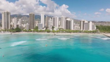 Etkileyici bir seyahat varış noktası kopyası. Waikiki sahilindeki hoş açık mavi okyanus manzarası nefes kesici. Arkadaki yeşil dağlarla mavi denizde modern bir şehir. Honolulu şehir hava aracı 4K