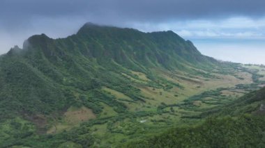 Nefes kesici tropikal doğa manzarası. İnsansız hava aracı destansı dağ sırtı üzerinde uçuyor. Oahu adasında açık hava macerası. Yeşil orman zirvesinin dramatik manzarası. Hawaii 'de bulutlu bir günde Kualoa Vadisi