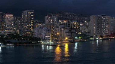 Şehir merkezinde, tropik ada Oahu 4K 'da. Gece Waikiki sahilinin manzarası. Geceleri aydınlatılmış güzel Honolulu modern binaları. Hava karardıktan sonra Hawaii 'nin en büyük şehrinden insansız hava aracı vuruldu.