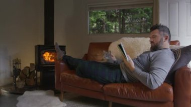 Rahat erkek kitap okurken sıcak bir orman kulübesindeki odun ocağında ısınıyor. Hafta sonu kaçamağındaki insanlar. Rahat deri vagonda kedi besleyen yakışıklı bir adam.