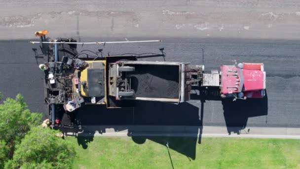 緑に囲まれた郊外通りにアスファルト舗装機で作業する乗組員の空中視点 フッテージ ストック動画