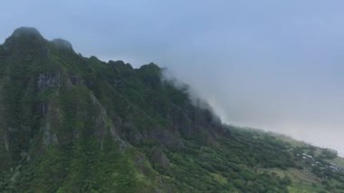 Yağmurlu çizgili uçurumlar, Jurassic Park manzaralı dağ manzarasında dramatik bir siluet oluşturuyor. Havadaki karamsar bulutlar 4K 'nın yüksek tepelerini örtüyor. Dramatik karamsar günde sinematik görkemli tropikal dağ zirvesi