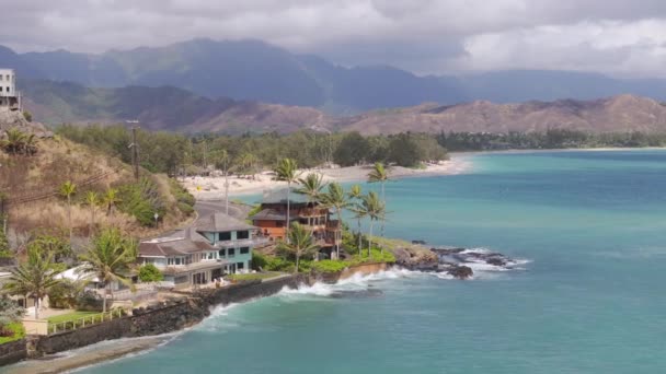无人机俯瞰着豪华海滨别墅 海浪冲刷着岩石海岸 周围环绕着风景秀丽的山脉 云天的兰尼凯海滩瓦胡岛 夏威夷自然景观4K — 图库视频影像