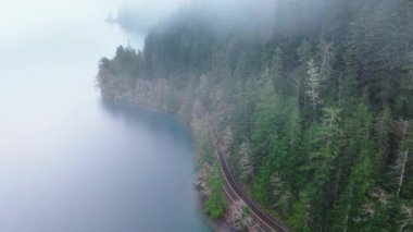Yolculuk konsepti havadan. Sisli bir günde güzel Crescent Gölü boyunca turistlerle dolu bir arazi aracı. Sinematik ve yeşil orman olimpiyat ulusal parkı. Washington yağmur ormanlarında gezginler