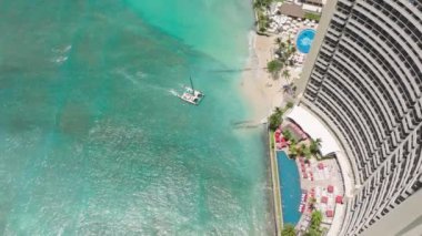 İnsanlar lüks Waikiki otelinin mavi havuzunda güneşleniyorlar. Hawaii seyahati. Plajın kenarında sonsuzluk havuzu. Güneşli bir günde Waikiki sahilindeki manzaralı bir tatil köyü. Oahu turizm geçmişi