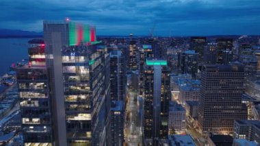 Washington 'ın alacakaranlık silueti. Günbatımının hava görüntüsü Seattle City USA 4K. Günbatımı sahnesindeki şehir manzarası. Geceleri Seattle finans sektörü. Renkli günbatımı gökyüzünde iş arkaplanı