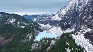 Washington doğası 4K hava görüntüsü, Mount Index 'in yüksek zirveleri. Kış günü dağ manzarası manzarası. Donmuş Göl. Evergreen Ormanı 'ndaki karlı kayalık zirvede. Sinema Kuzey Şelaleleri Dağları