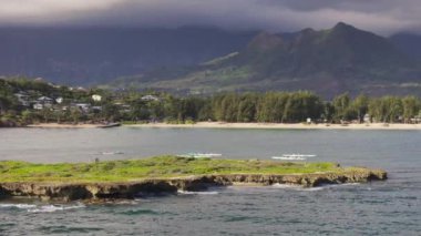 Kailua Körfezi 'ndeki Popoia Adası' nın yakın görüntüsü. Hareket halindeki güzel Hawaii adası dağları. İnsansız hava aracı, doğal sığınağı olan küçük düz yeşil kayalık adanın etrafında uçuyor. Lanikai plajı yaz günü