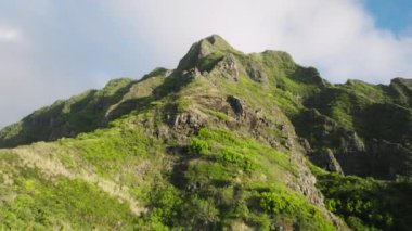 Güneşli yaz gününde destansı dağ zirveleri. İnsansız hava aracı dağ sırtı boyunca manzaralı zirvelerle uçuyor. Yeşillik arka planı yemyeşil. Hawaii doğa güzelliği altın ışıkta. Oahu seyahat arka planı USA 4K