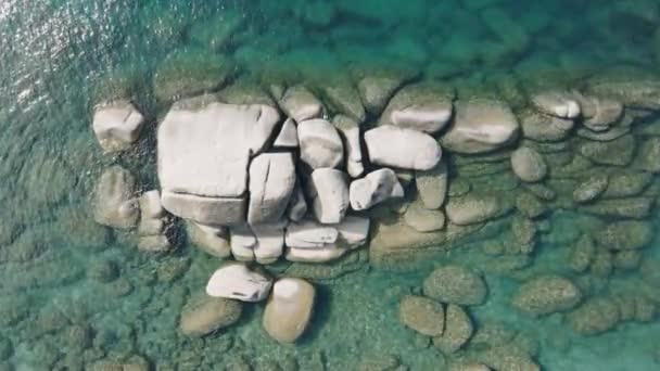 空中撮影は タホ湖の澄んだ水と大きな石の過去のクラスタを巧みに航行するカヤックの旅をキャプチャします フッテージ — ストック動画