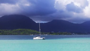 Beyaz bir tekne Oahu, Hawaii, ABD 'nin sakin sularında huzur içinde yüzüyor. Tekne zarif bir şekilde yüzeyde süzülür ve ardında hafif dalgalanmalar yaratır..