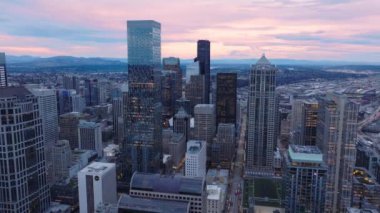 Bir hava manzarası Seattles kentsel manzarasının alacakaranlık özünü yakalar, yansıtıcı gökdelenleri ve uzak sıradağları vurgular. Şehir canlılığı, doğal sükunetle birleşir. 4K görüntü. 